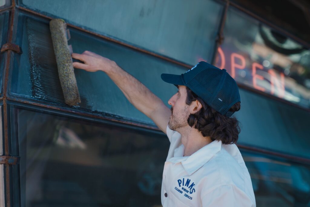 Technician cleaning a window with a sponge in Pittsburgh, PA.